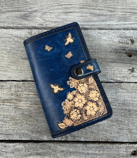 Blue wallet with floral designs on a wooden surface