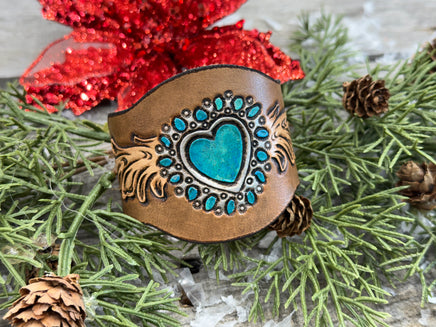 Hand-carved leather cuff bracelet with turquoise heart, orange flowers, and antique copper snaps, handmade by Cherokee Rose Custom Leather in East Texas.
