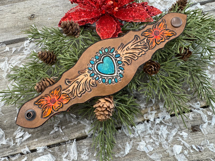 Hand-carved leather cuff bracelet with turquoise heart, orange flowers, and antique copper snaps, handmade by Cherokee Rose Custom Leather in East Texas.