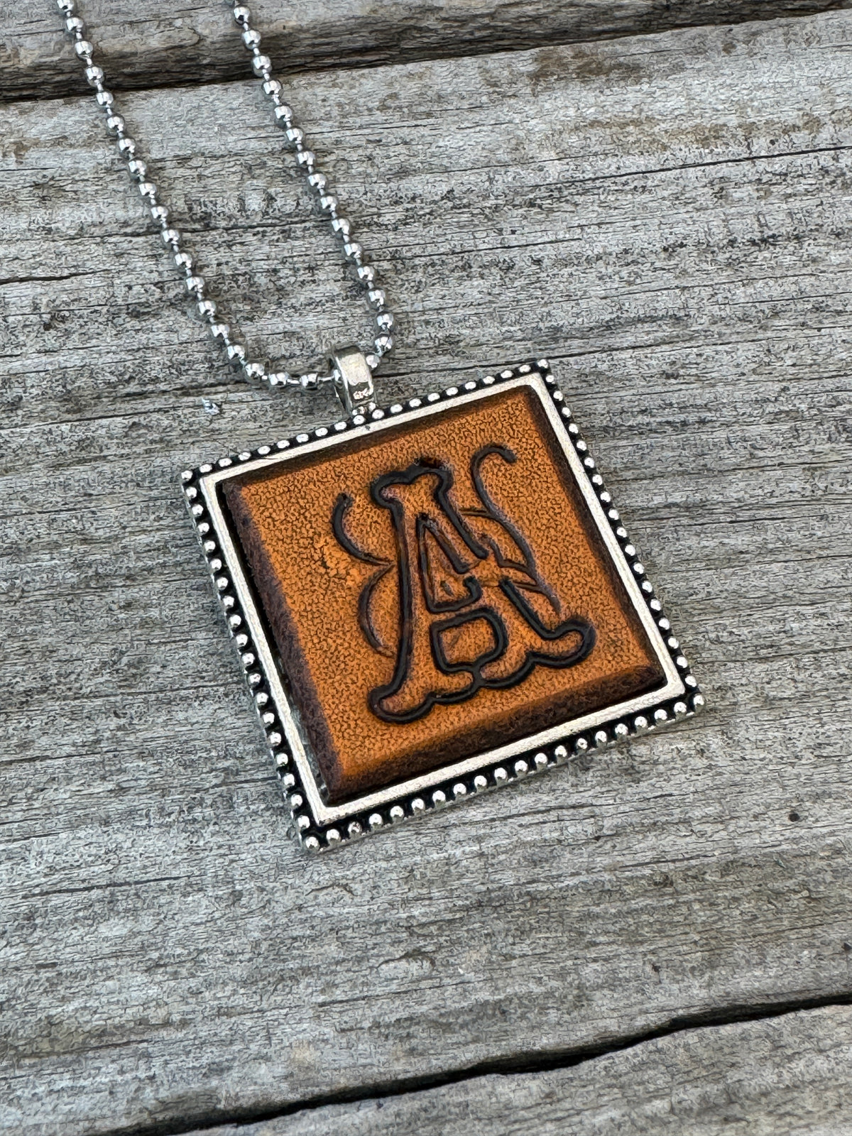 Floral Script letter A hand-stamped leather pendant necklace in a silver-tone square frame
