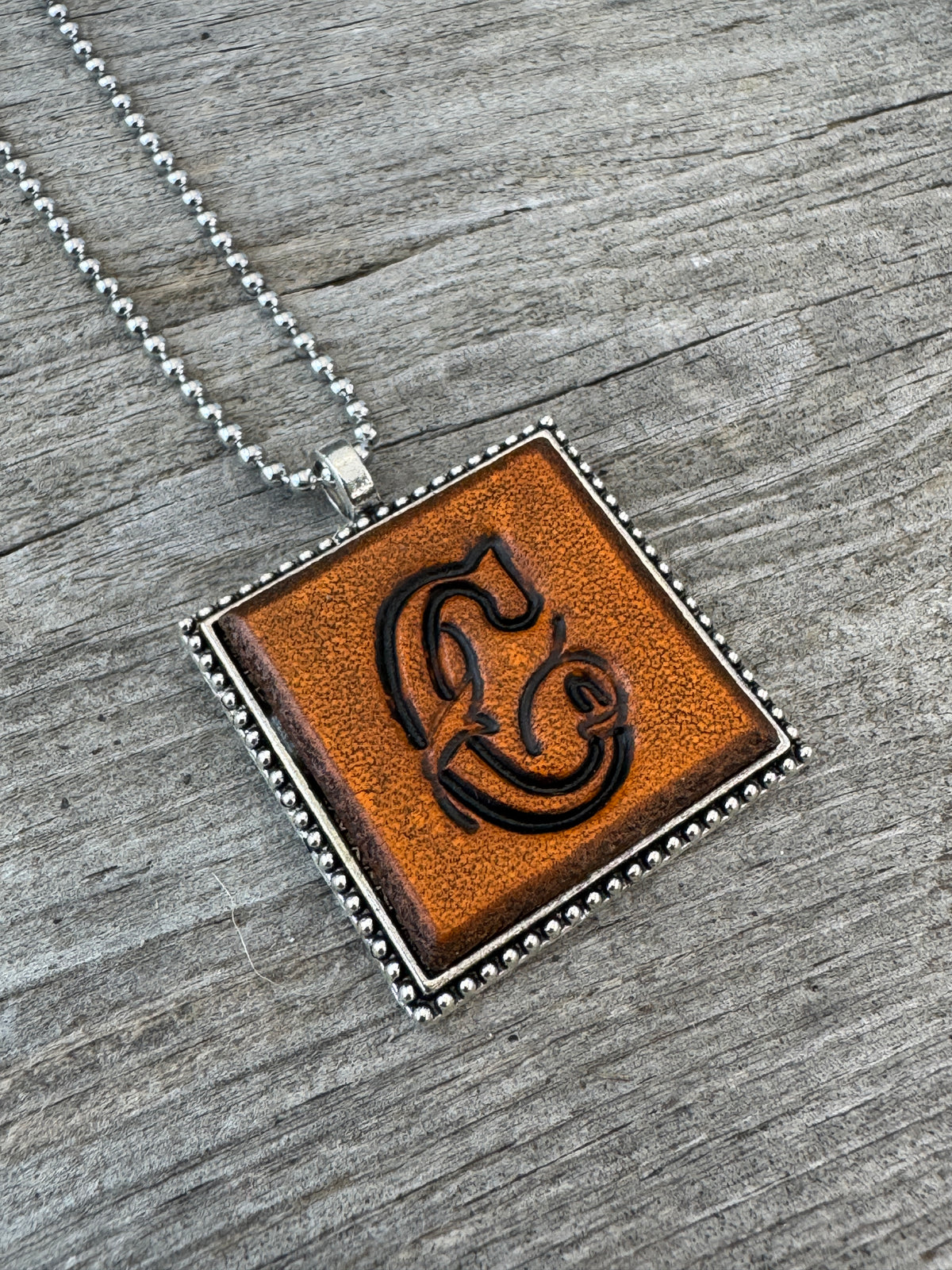 Floral Script letter C hand-stamped leather pendant necklace in a silver-tone square frame