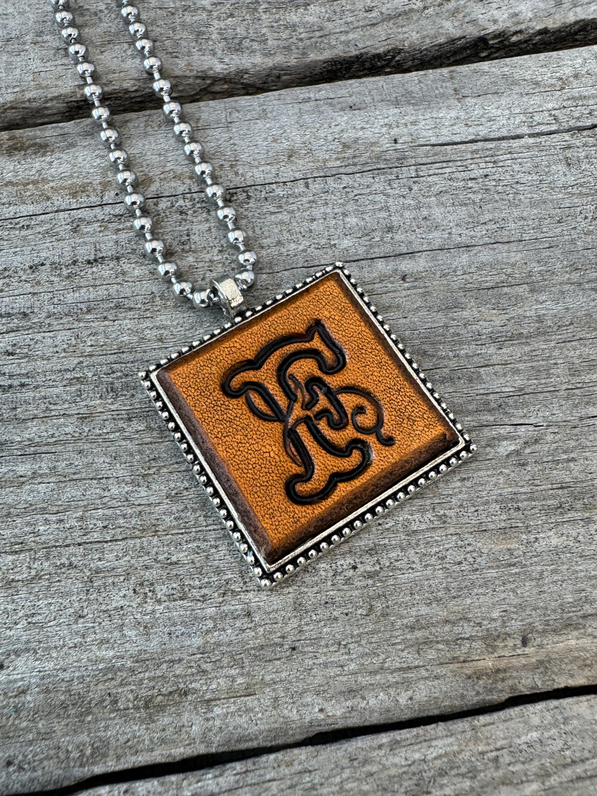 Floral Script letter F hand-stamped leather pendant necklace in a silver-tone square frame
