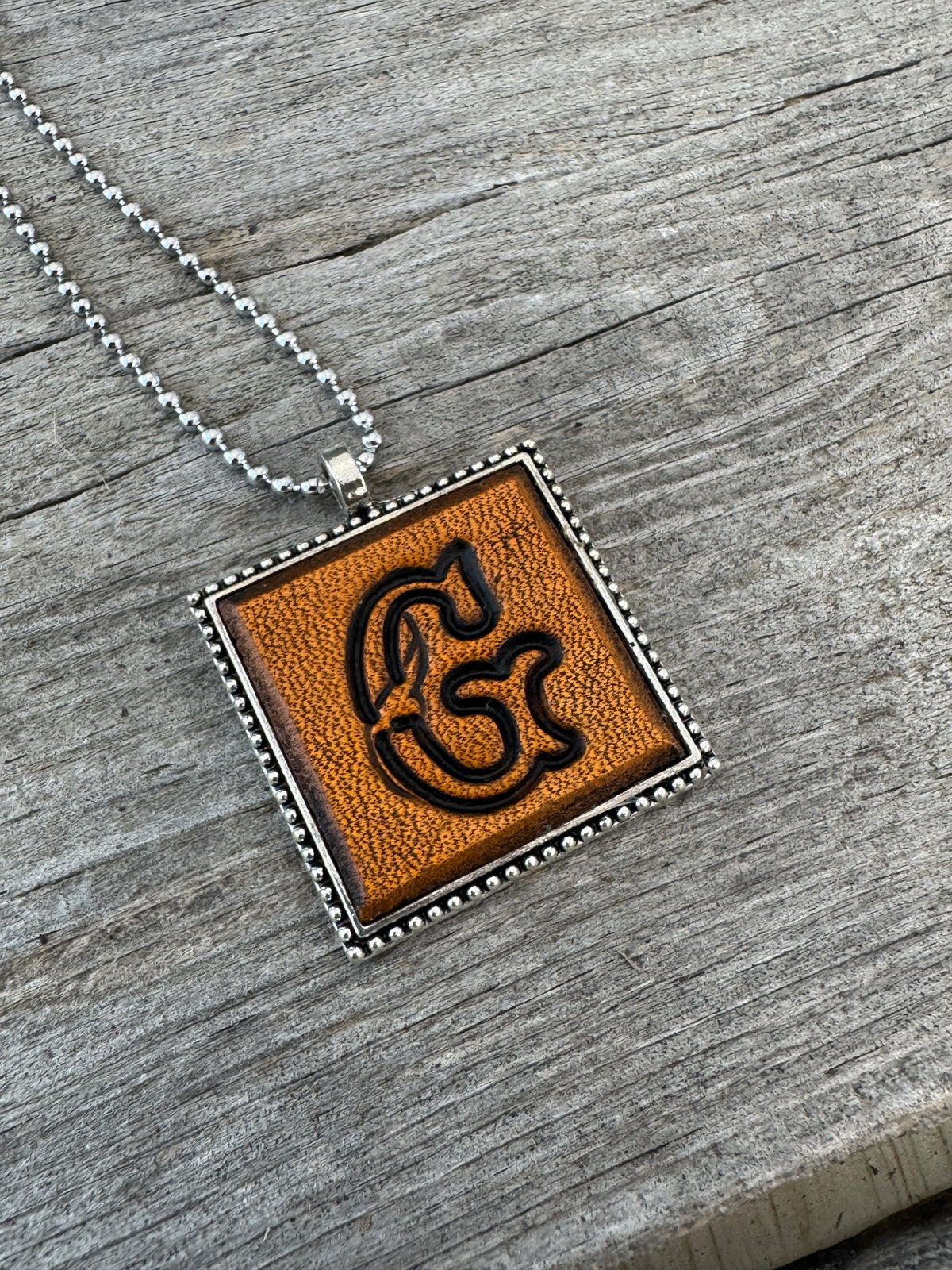 Floral Script letter G hand-stamped leather pendant necklace in a silver-tone square frame