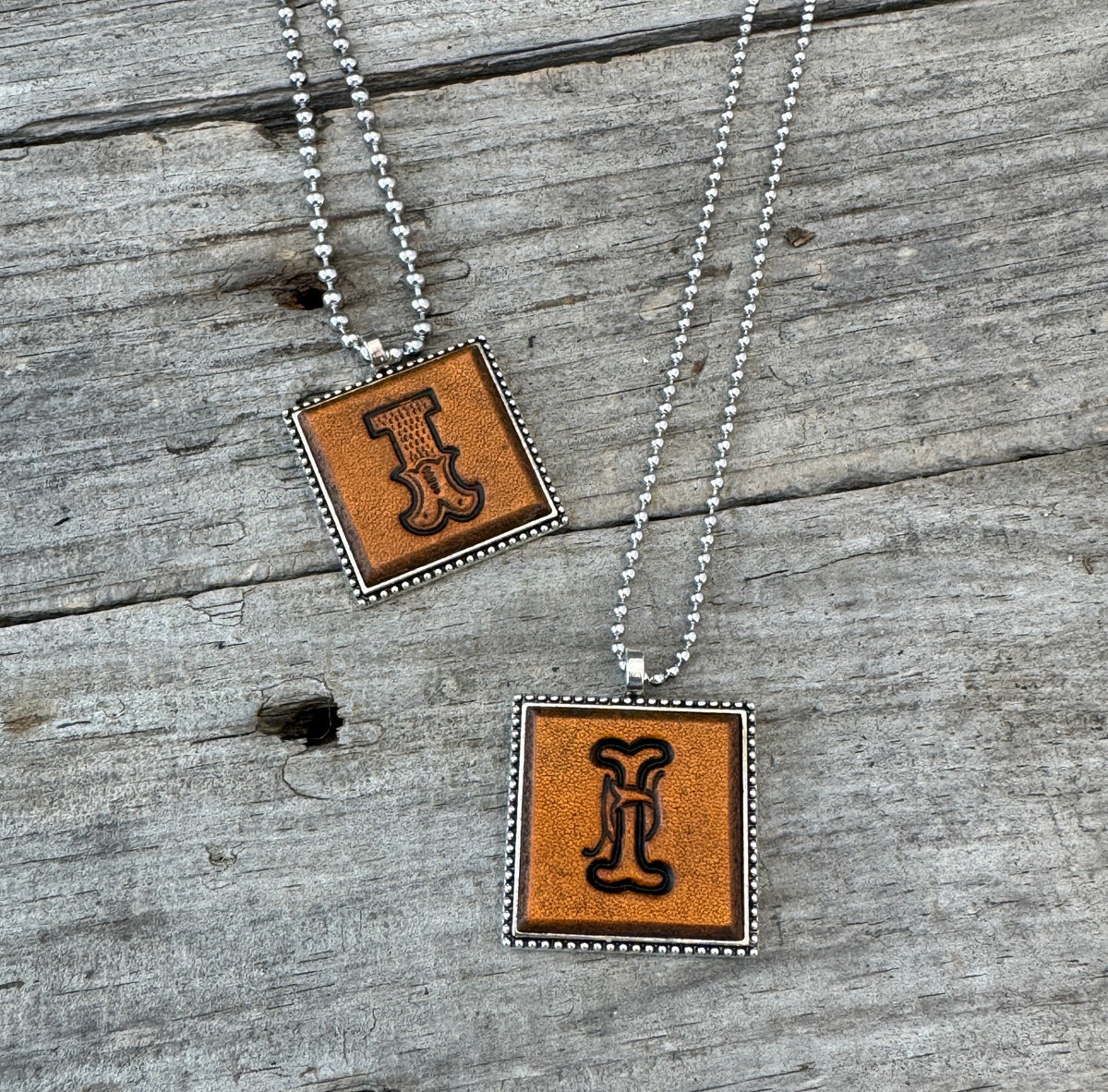 Two handmade Letter I leather initial necklaces featuring Western Block and Floral Script lettering on genuine brown leather pendants.