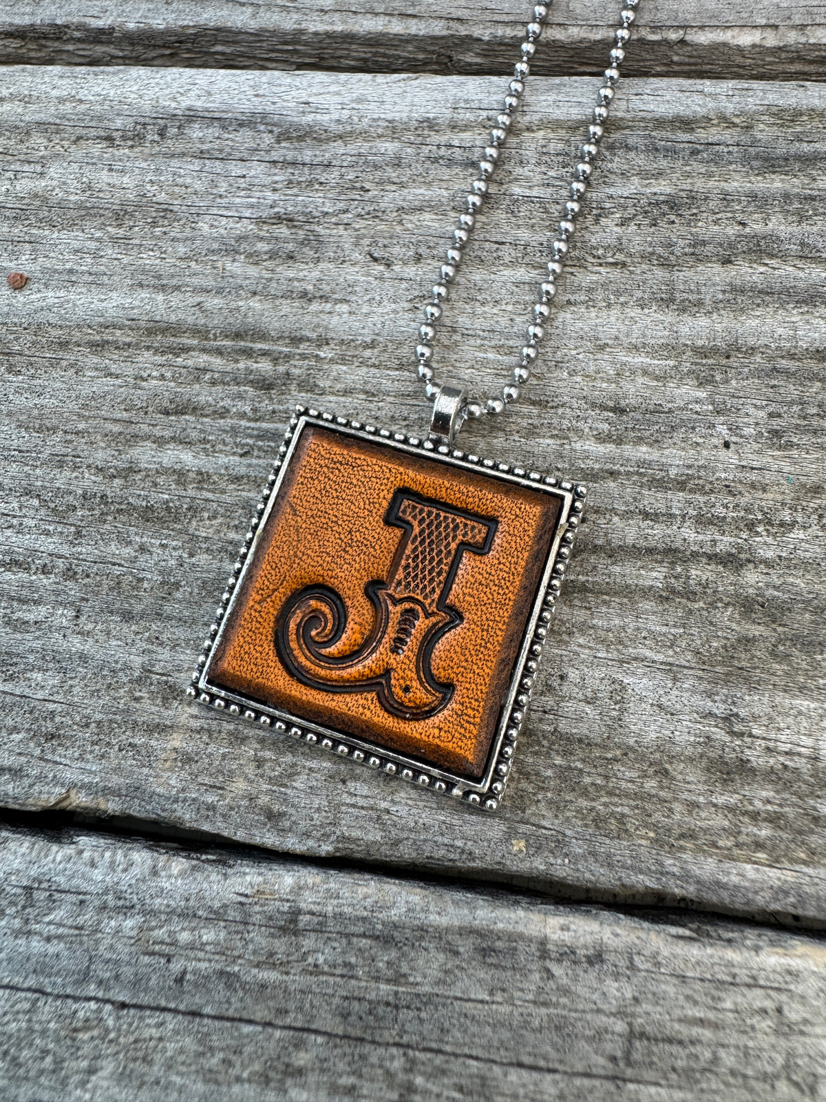 Western Block Letter J leather initial necklace featuring bold cowboy-inspired lettering with a decorative curled flourish stamped into genuine leather.