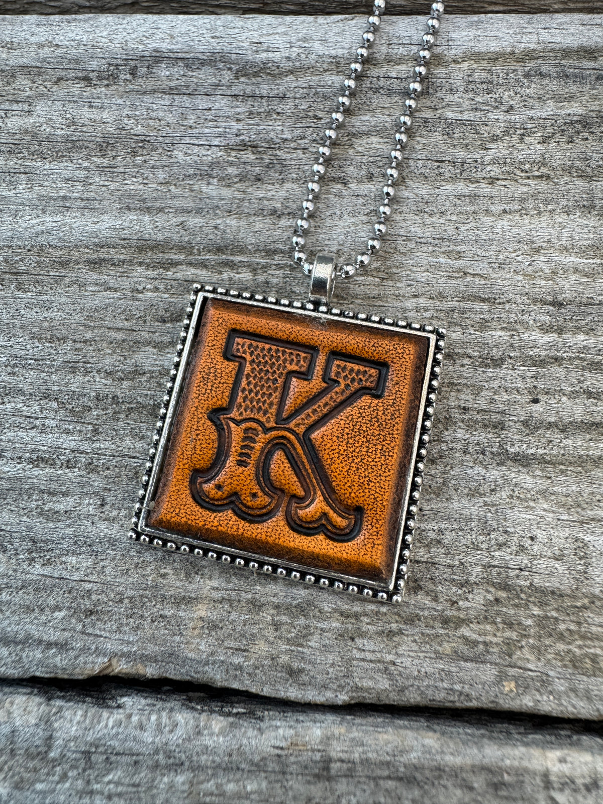Western Block Letter K leather initial necklace featuring bold cowboy-style lettering with detailed basketweave stamping and decorative flourishes.