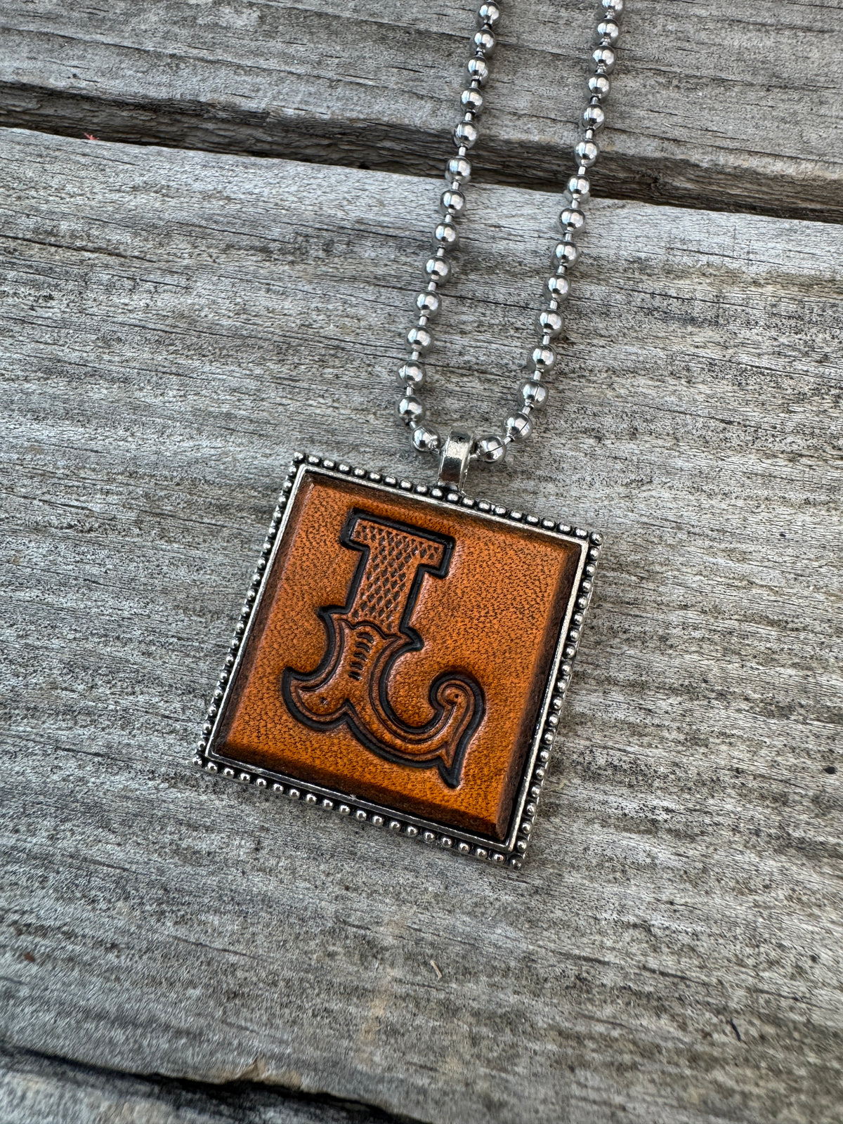 Close-up of Western Block Letter L stamped leather pendant with silver-tone frame