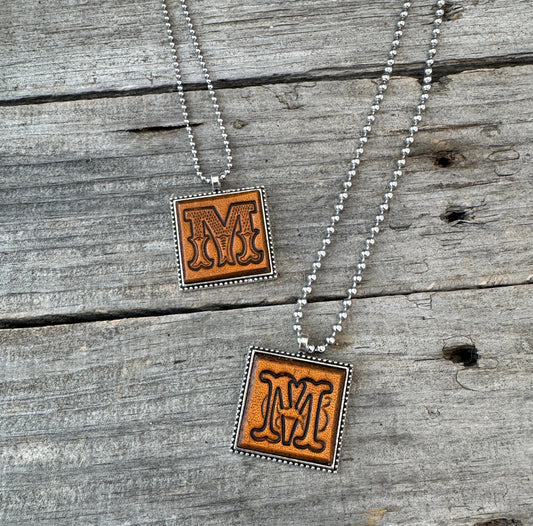 Two handmade Letter M leather initial necklaces in Western Block and Floral Script fonts