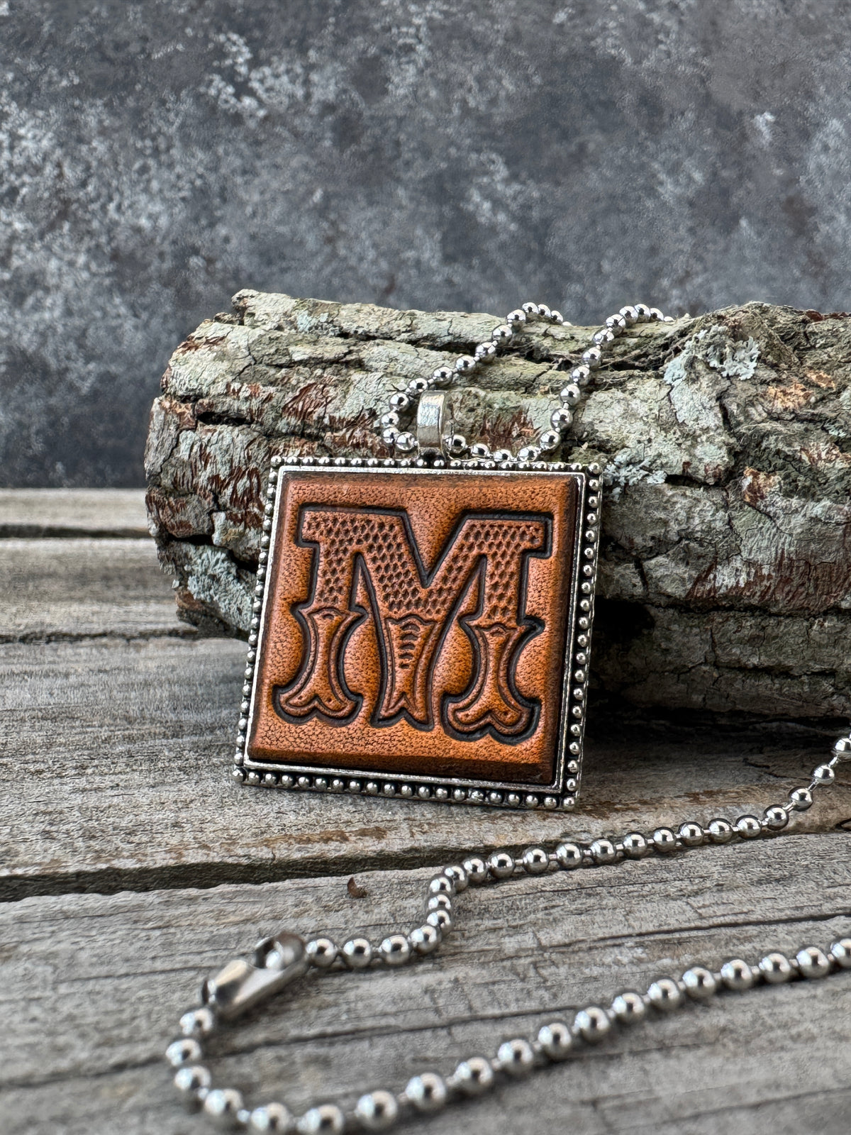 Western Block Letter M leather initial necklace styled on rustic wood