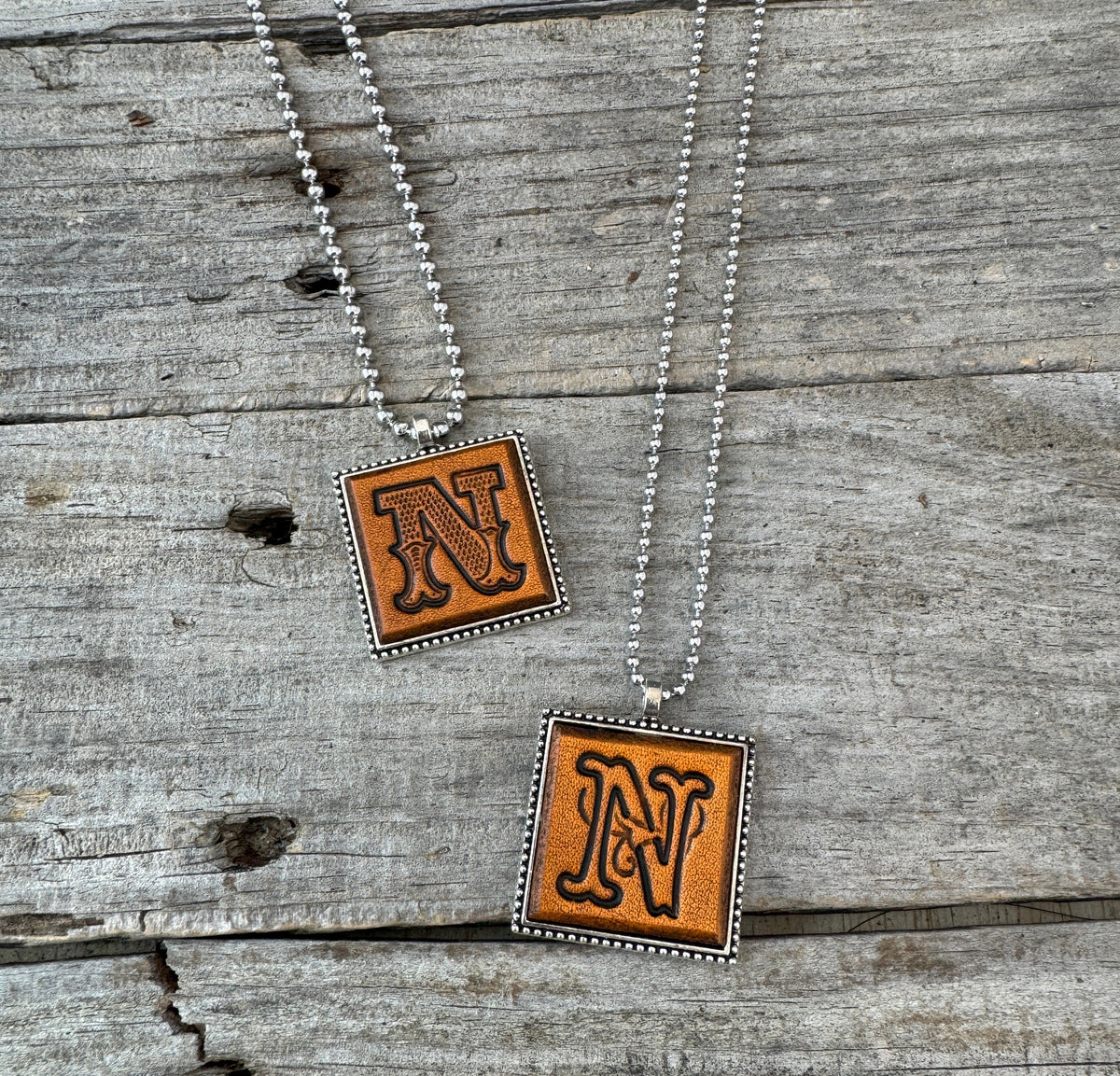 Two handmade Letter N leather initial necklaces showing Western Block and Floral Script fonts