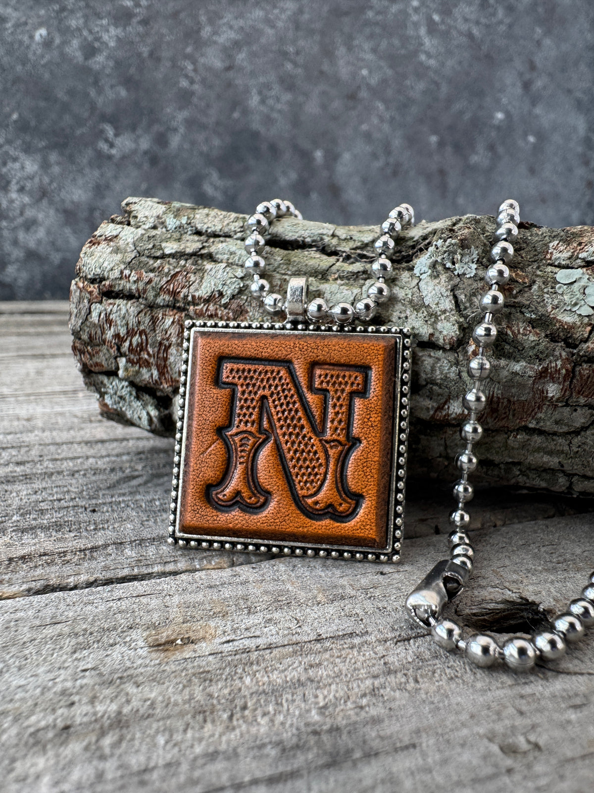Western Block Letter N leather initial necklace styled on rustic wood