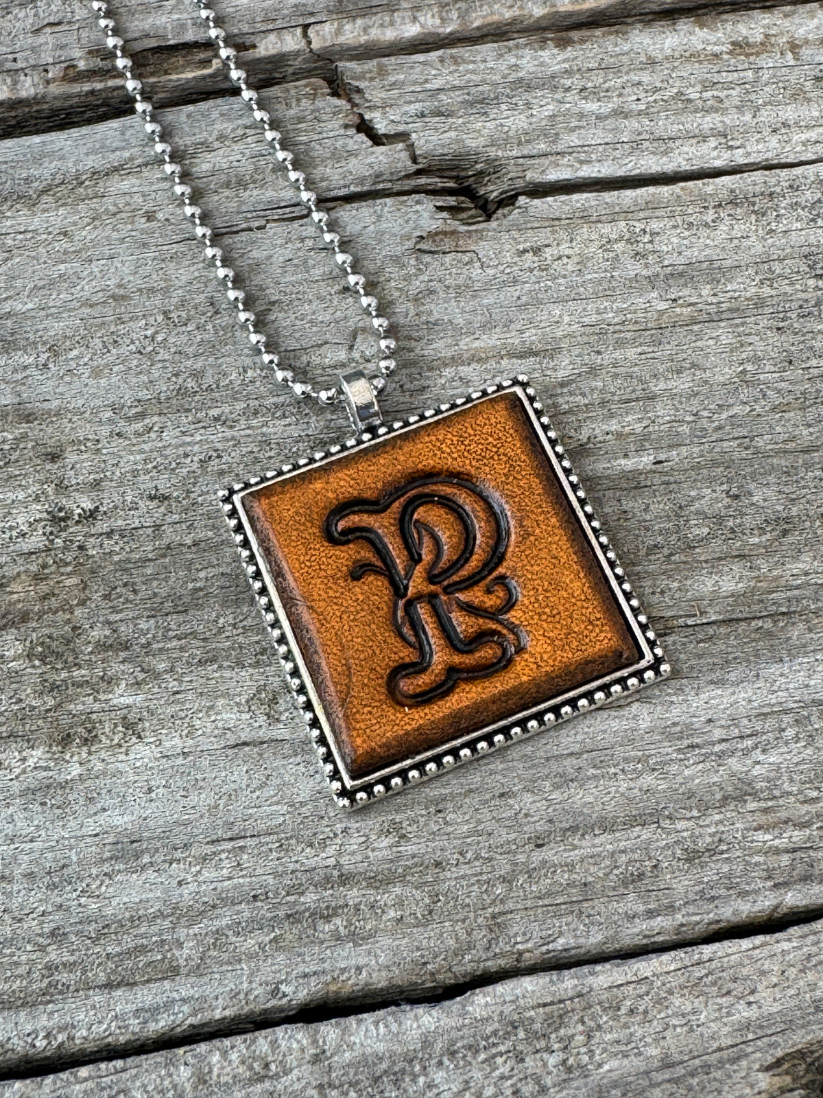 Close-up of Floral Script Letter P leather initial pendant with antiqued lettering