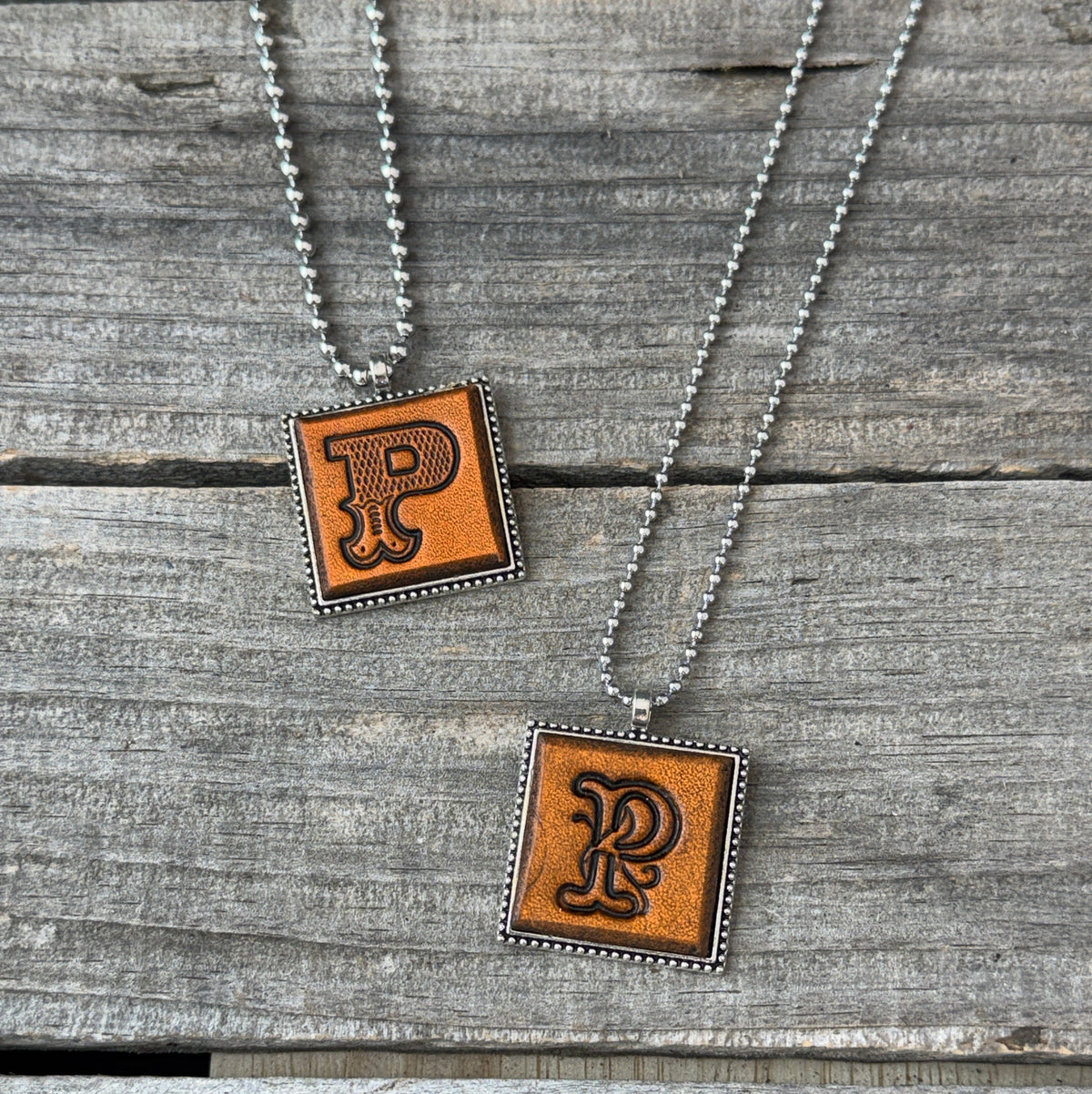 Two handmade Letter P leather initial necklaces in Western Block and Floral Script fonts