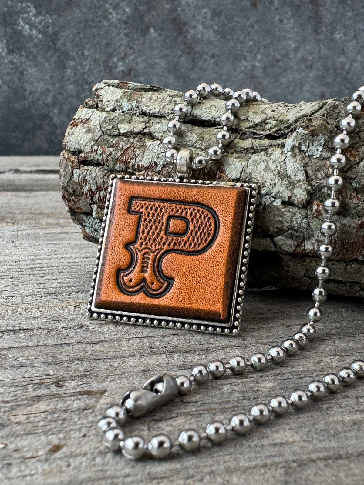 Western Block Letter P leather initial necklace styled on rustic wood
