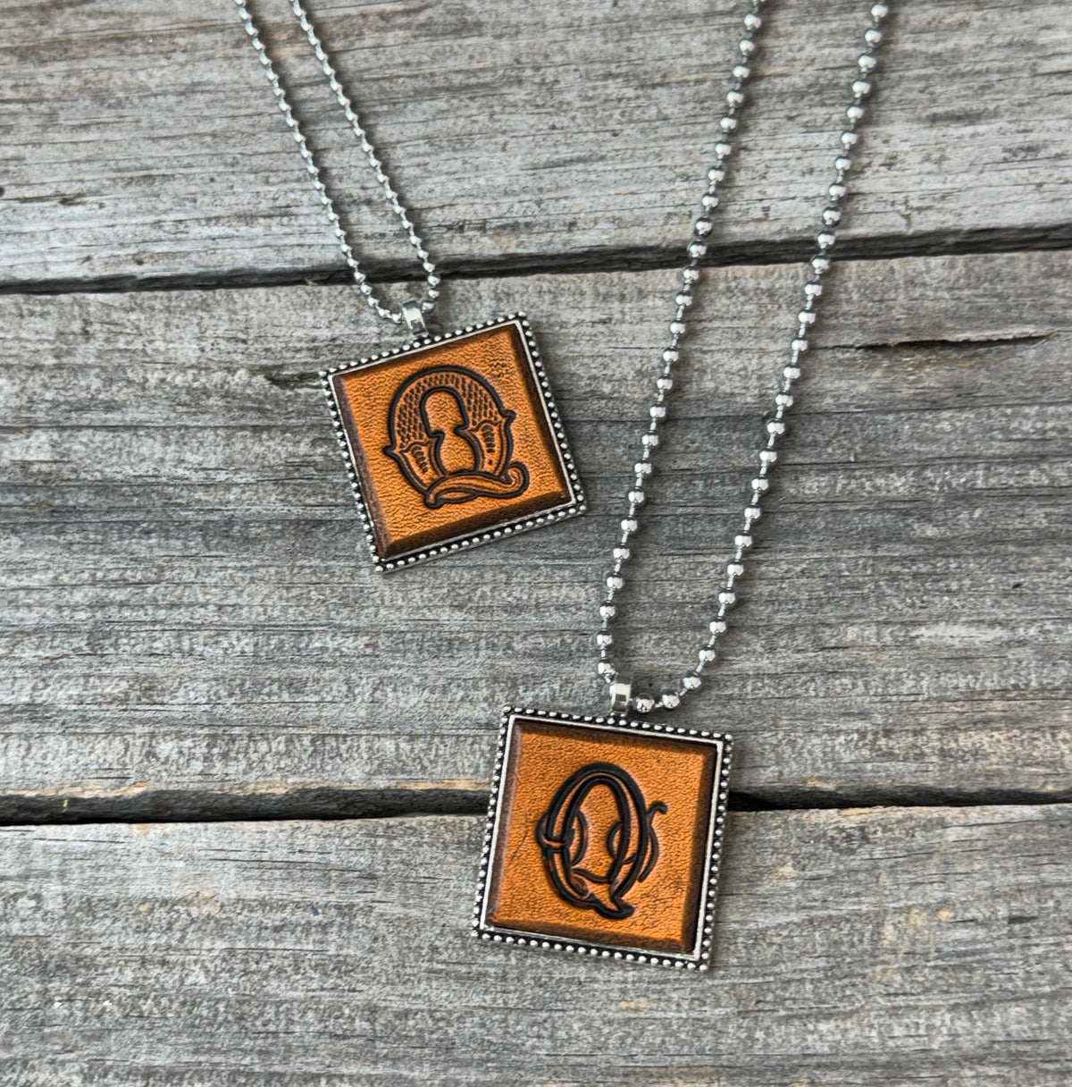 Two handmade Letter Q leather initial necklaces in Western Block and Floral Script fonts