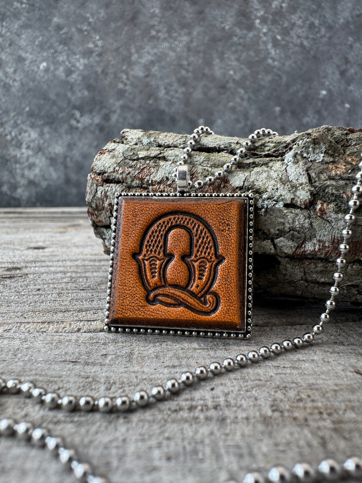 Western Block Letter Q leather initial necklace styled on rustic wood