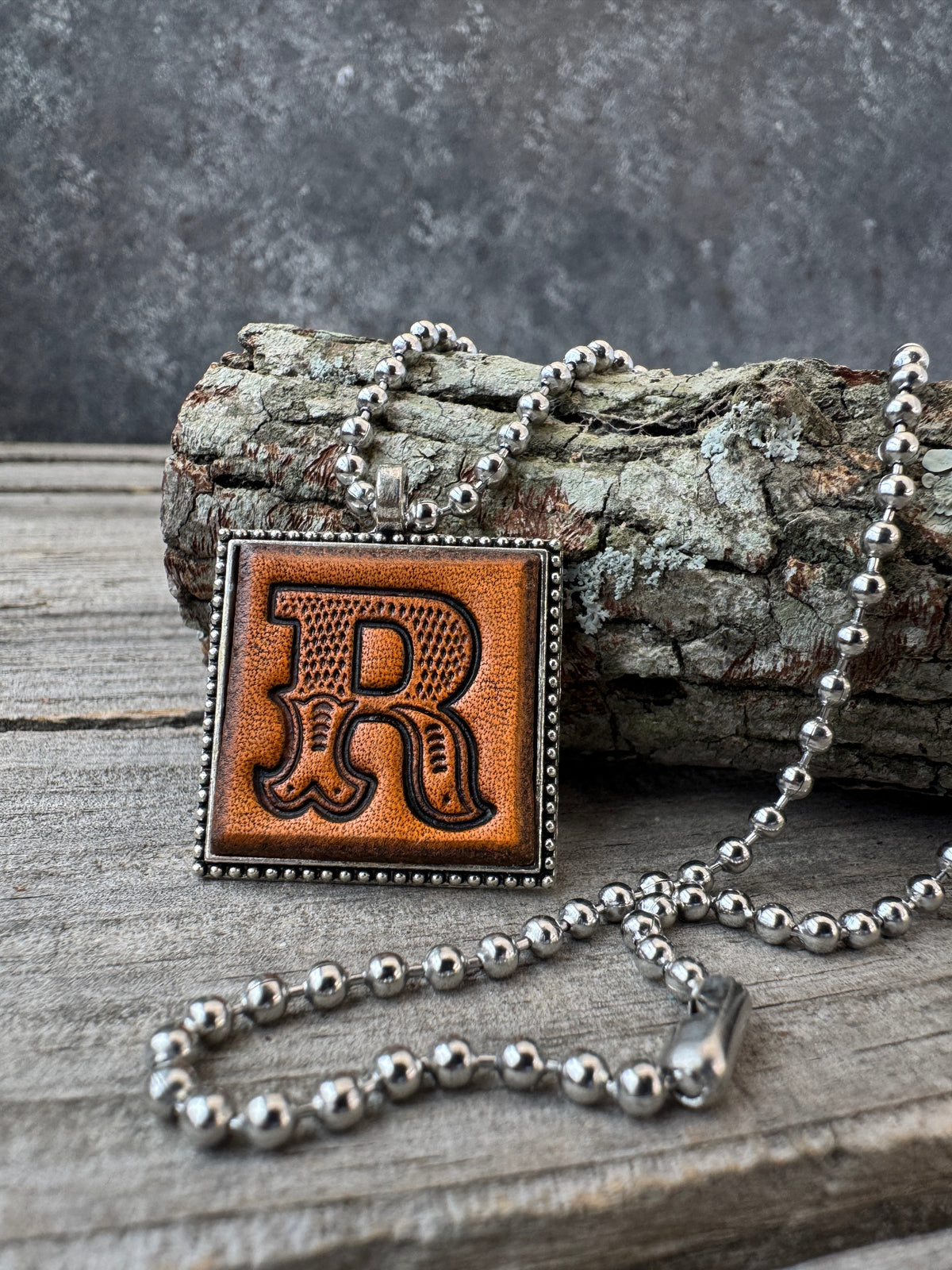 Western Block Letter R leather initial necklace styled on rustic wood