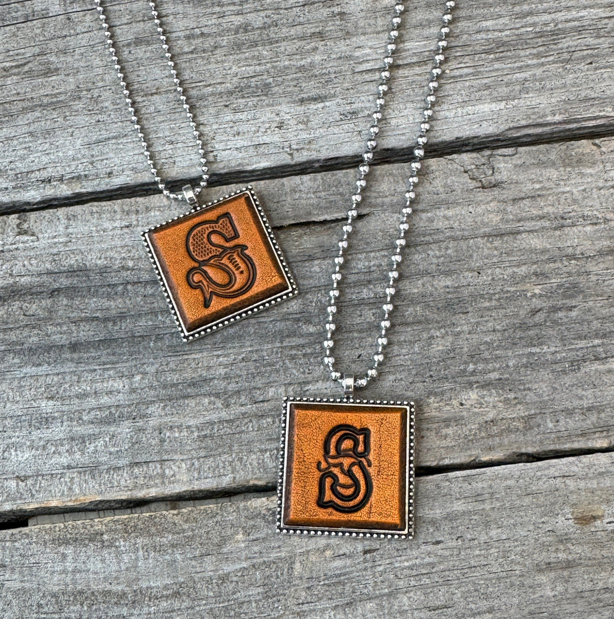 Two handmade Letter S leather initial necklaces in Western Block and Floral Script fonts