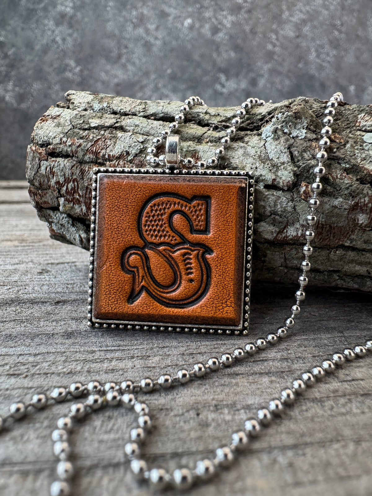 Western Block Letter S leather initial necklace styled on rustic wood
