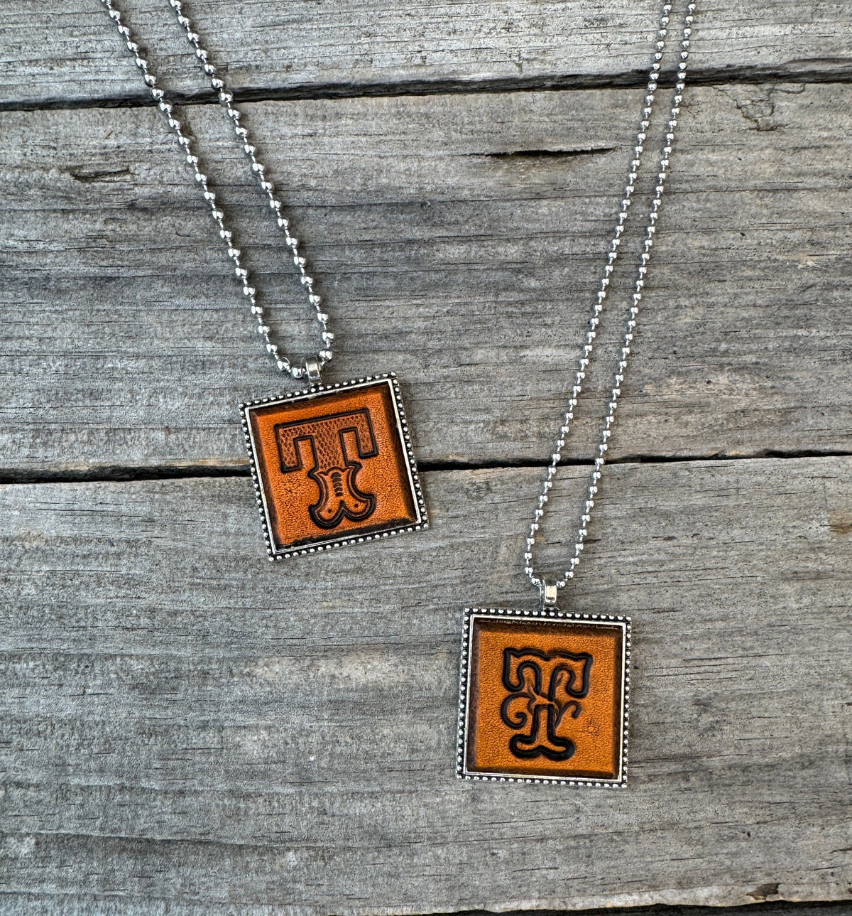 Two handmade Letter T leather initial necklaces in Western Block and Floral Script fonts