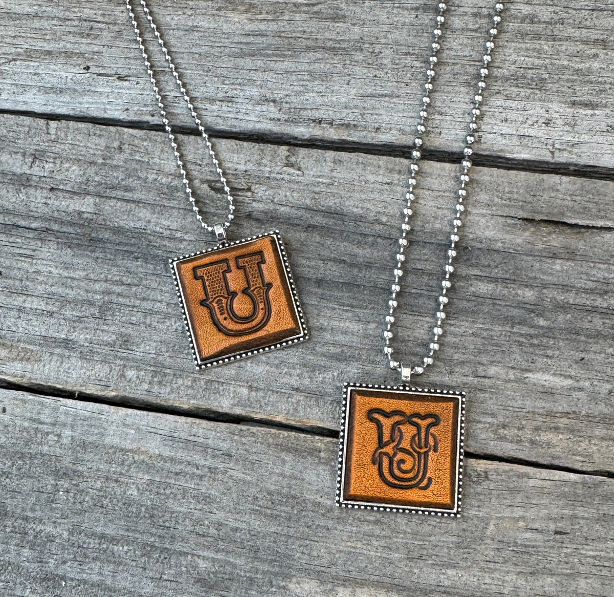 Two handmade Letter U leather initial necklaces in Western Block and Floral Script fonts