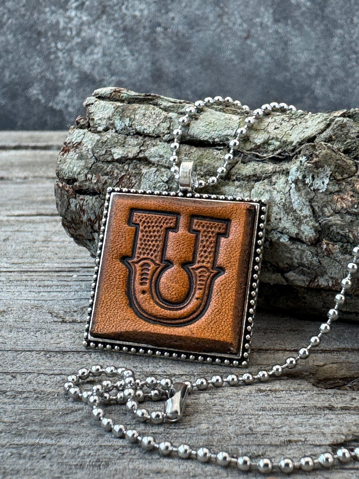 Western Block Letter U leather initial necklace styled on rustic wood