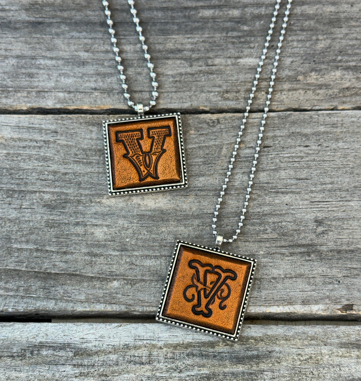 Two handmade Letter V leather initial necklaces in Western Block and Floral Script fonts