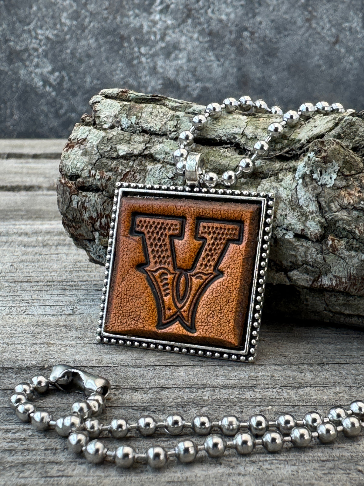 Western Block Letter V leather initial necklace styled on rustic wood