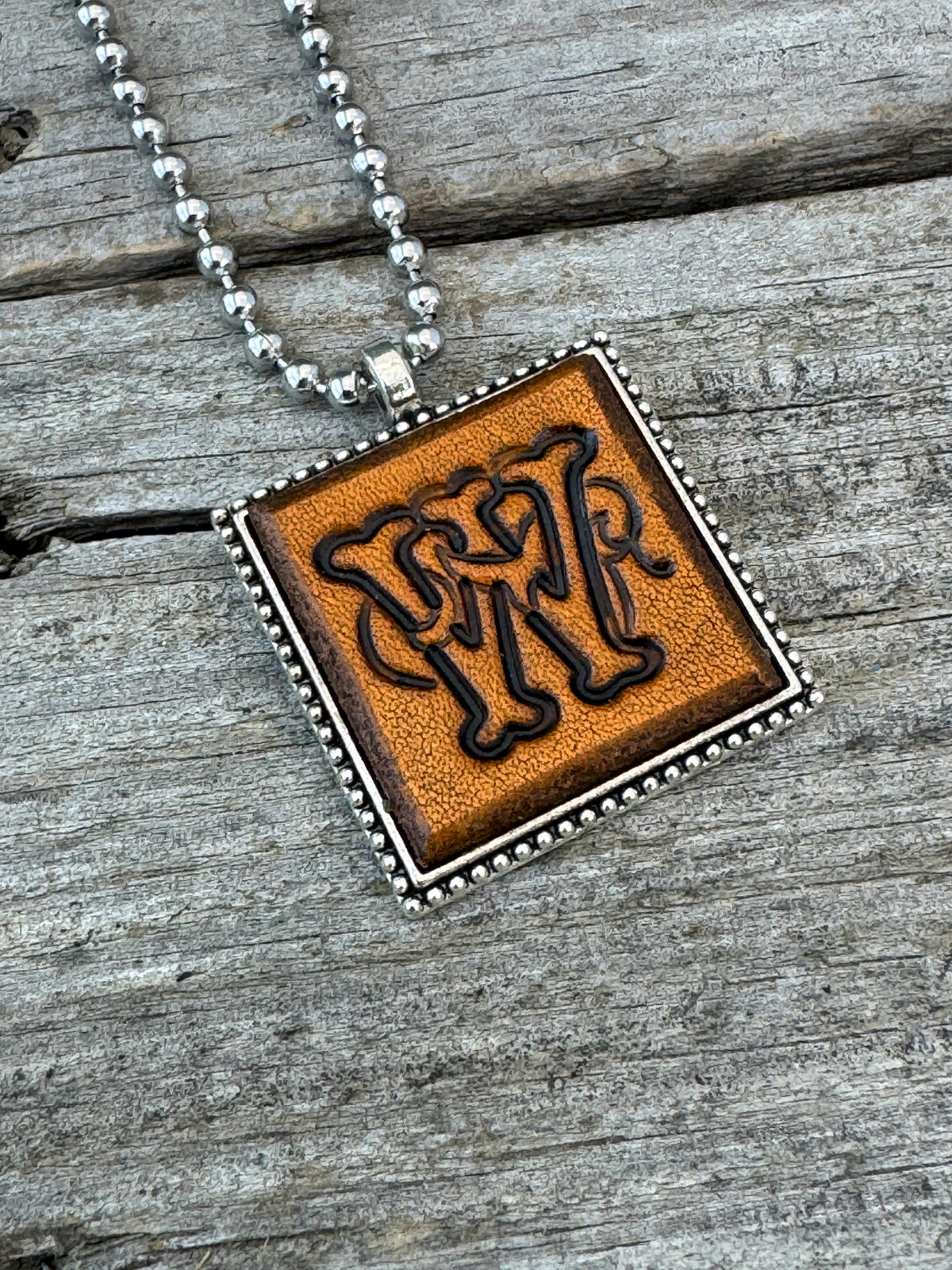 Close-up of Floral Script Letter W leather initial pendant with antiqued lettering