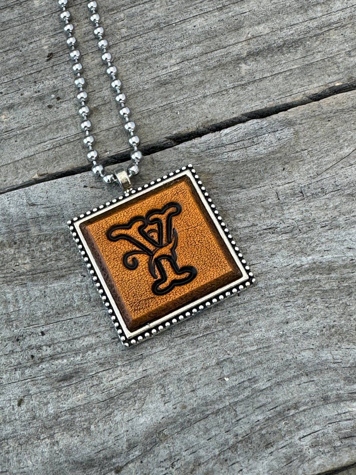 Close-up of Floral Script Letter Y leather initial pendant with antiqued lettering