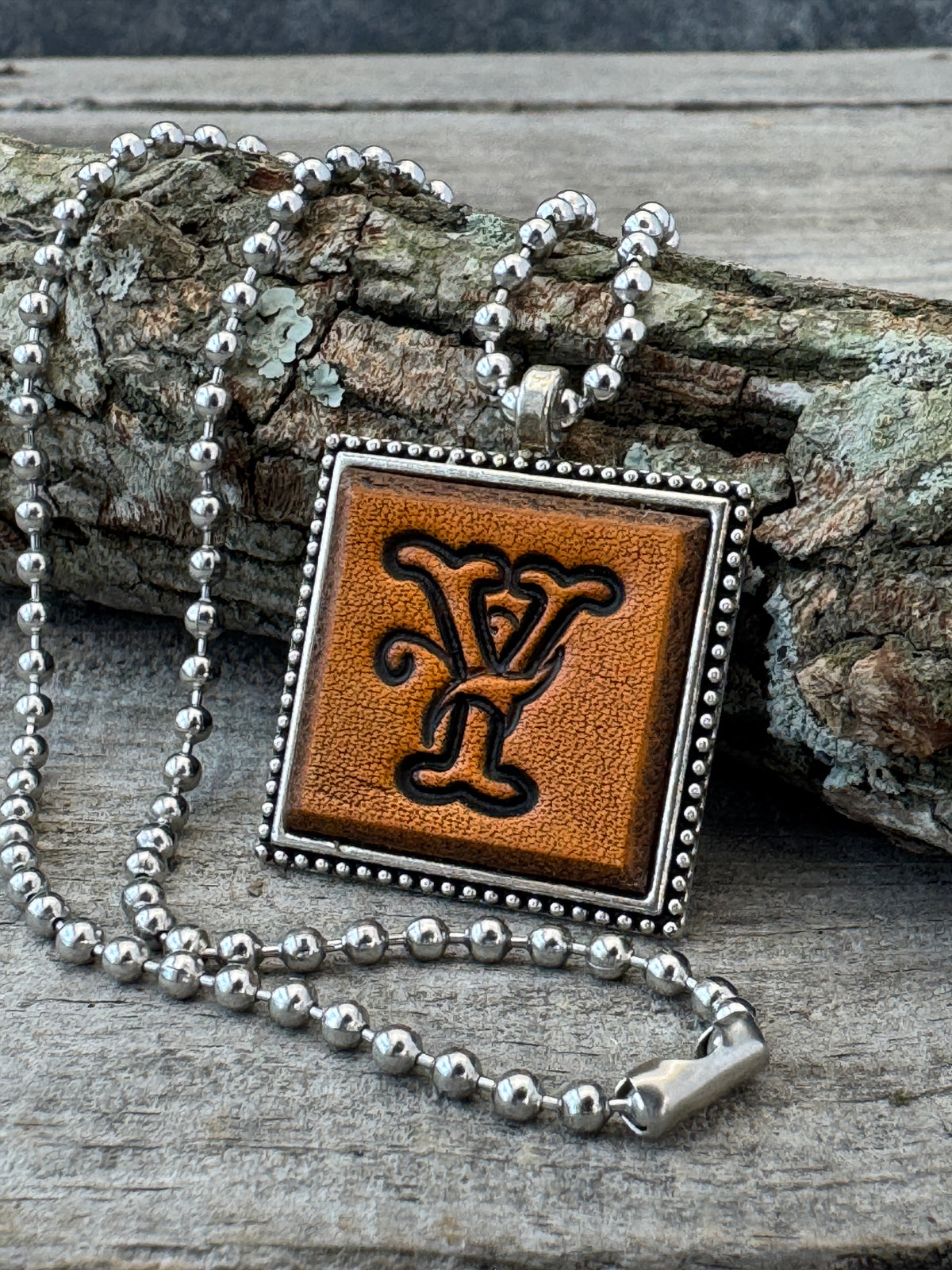 Floral Script Letter Y leather initial necklace styled against natural wood