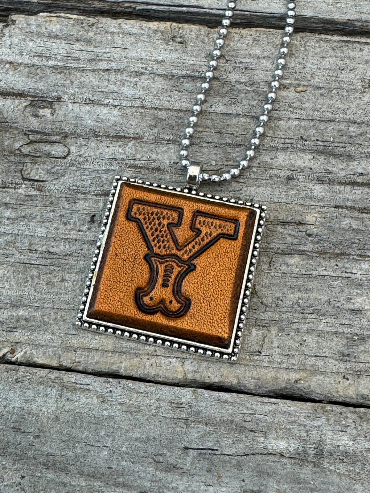 Close-up of Western Block Letter Y hand-stamped leather pendant in silver-tone square frame