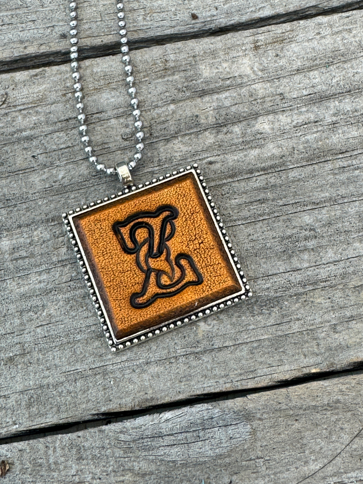 Close-up of Floral Script Letter Z leather initial pendant with antiqued lettering