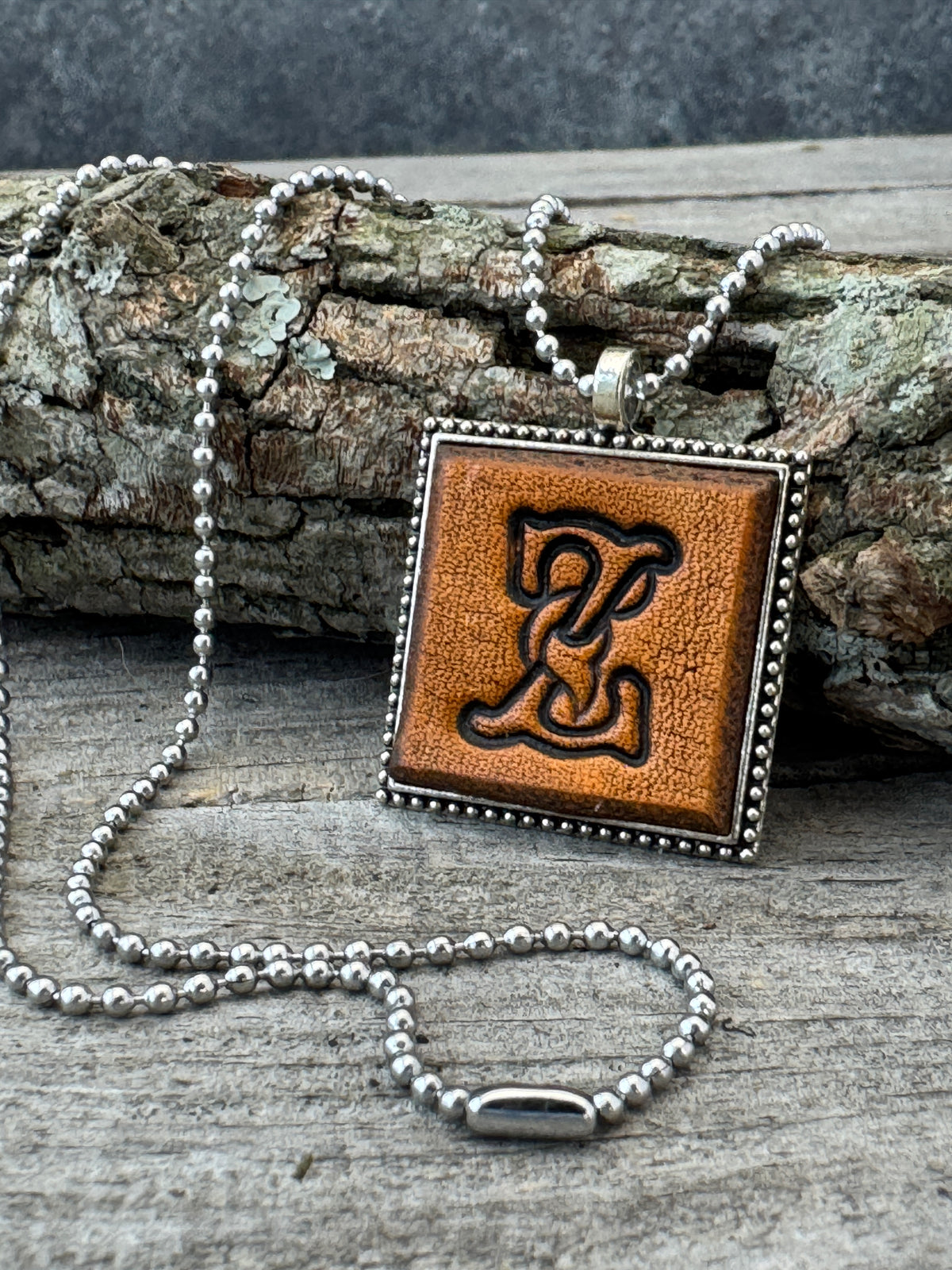 Floral Script Letter Z leather initial necklace styled against natural wood