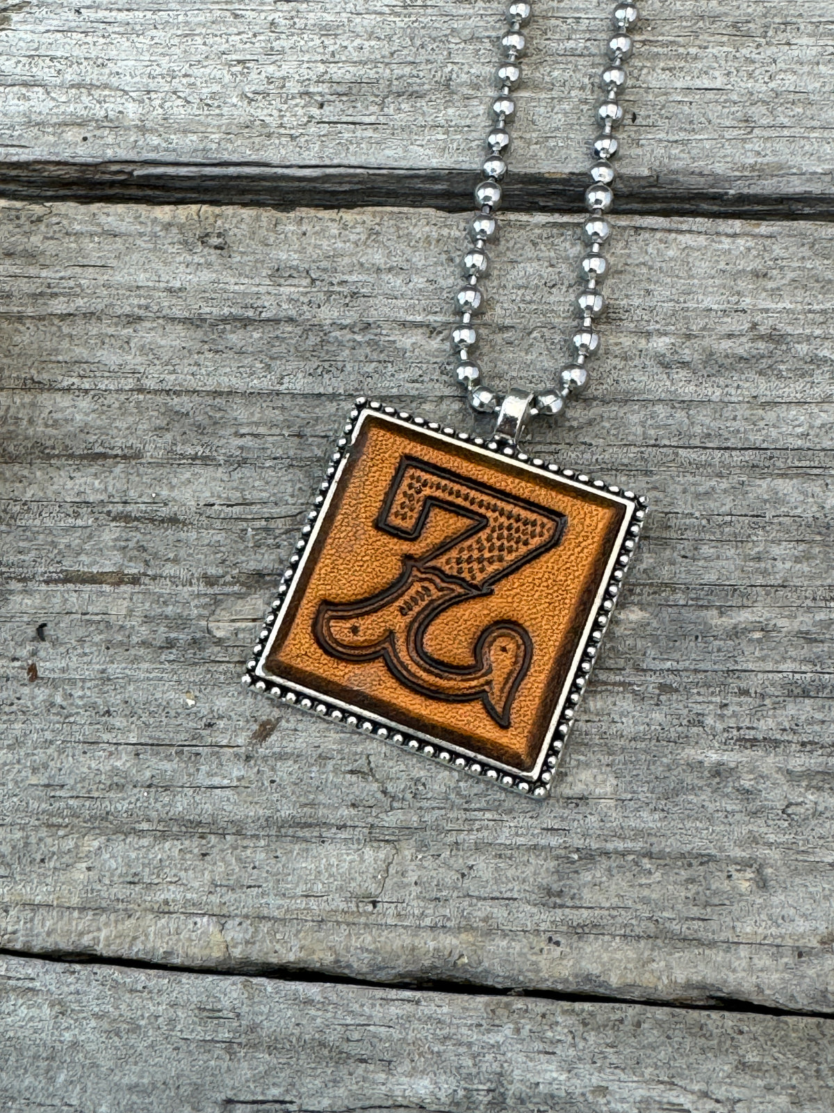 Close-up of Western Block Letter Z hand-stamped leather pendant in silver-tone square frame