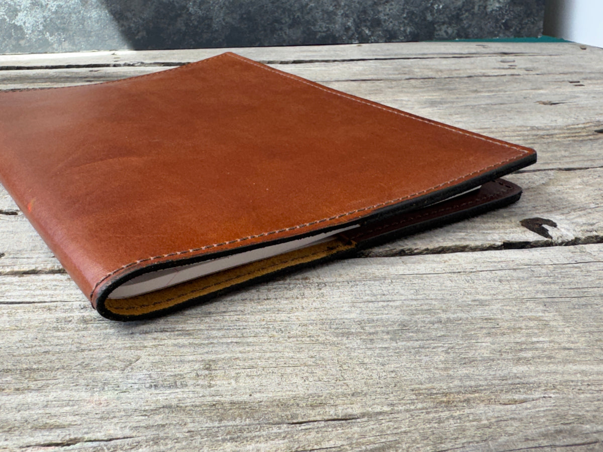 Medium brown leather composition notebook cover showing leather thickness and finished edges