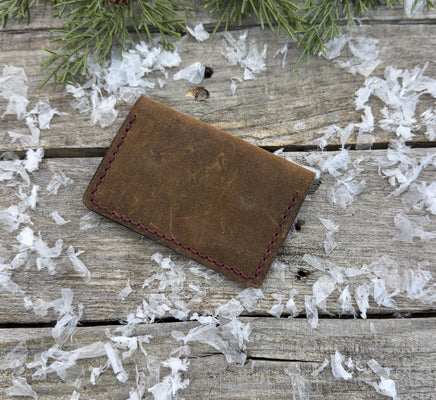 Handmade brown oil-tanned leather card wallet with double snap closure and burgundy stitching, crafted by Cherokee Rose Custom Leather in East Texas.