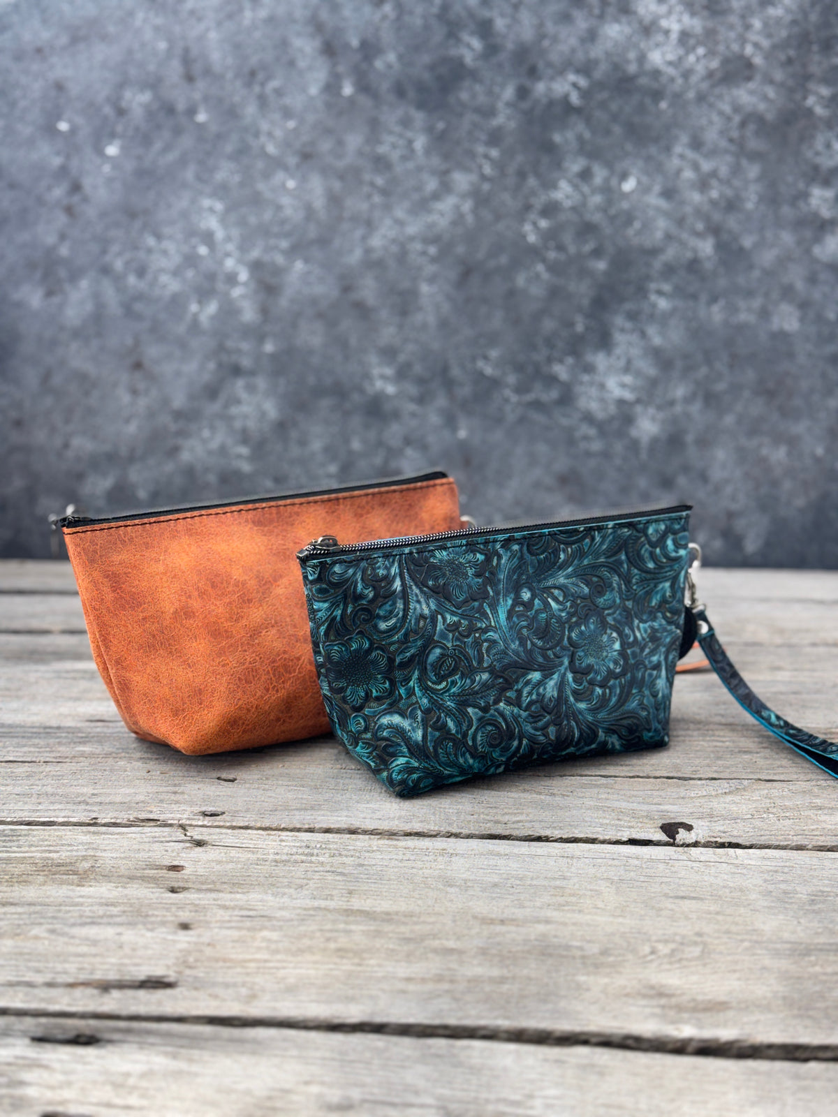 Two medium handmade leather cosmetic bags in turquoise floral and rustic orange with zippered tops