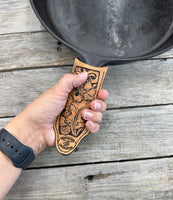 Hand tooled leather cast iron skillet handle cover with oak leaf and acorn carving, light tan dye, handmade by Cherokee Rose Custom Leather in East Texas.