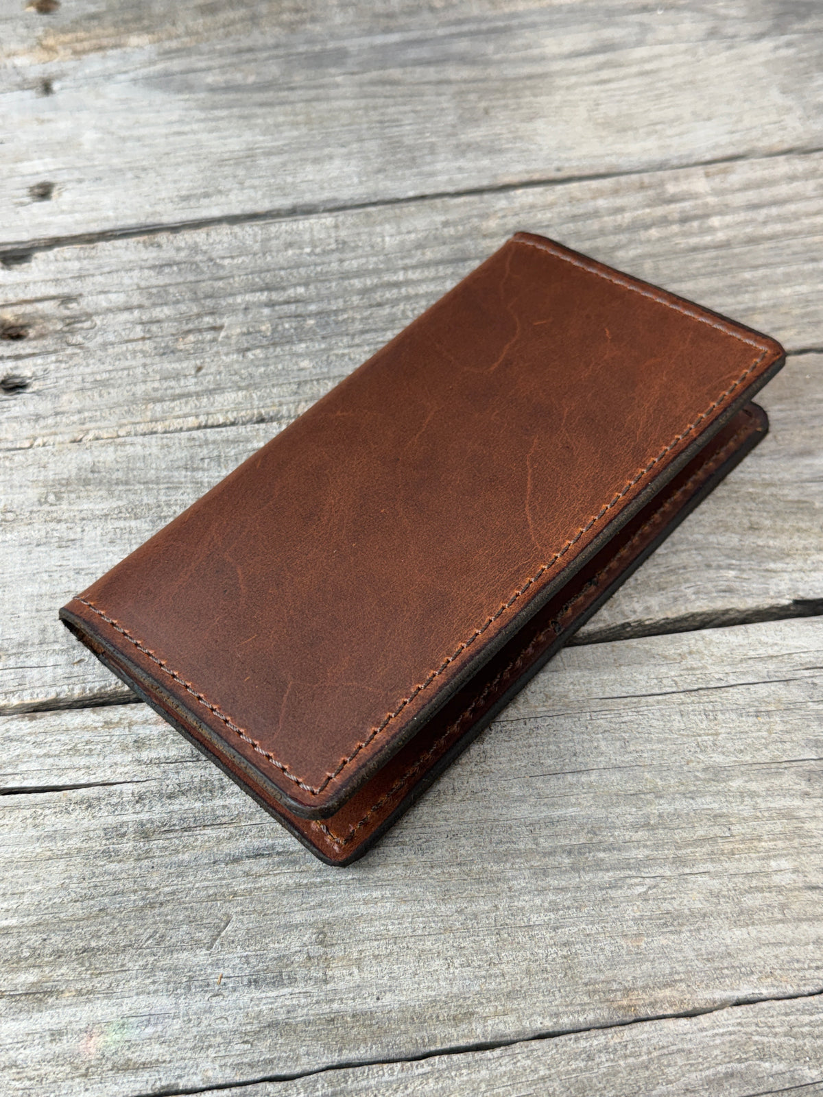 Rustic brown oil tanned leather checkbook cover on rustic wood background