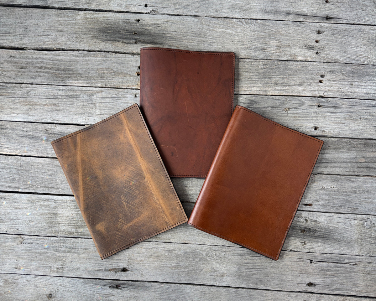Three handmade oil tanned leather composition notebook covers in rustic brown, redwood and smooth medium brown