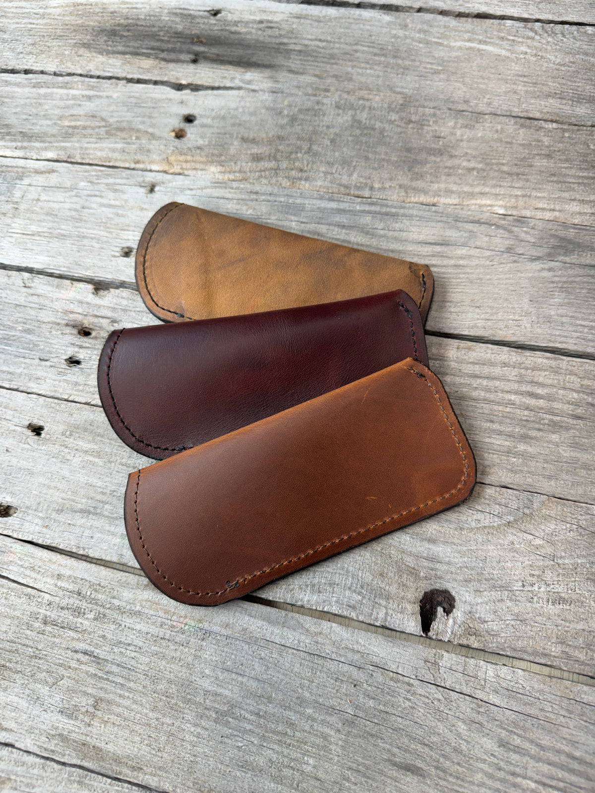 Three handmade oil tanned leather eyeglass cases in Bayou Red, Rodeo Tan and Rustic Brown