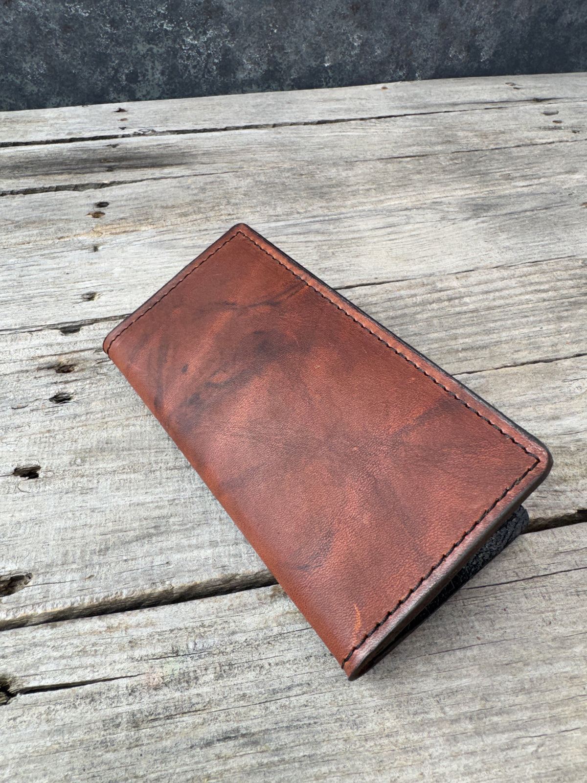 Redwood oil tanned leather roper wallet lying on rustic wood background
