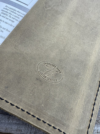 Close-up of a leather cover with a brand logo on a wooden surface