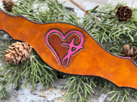 Hand-carved leather cuff bracelet with pink heart and cross design, silver snaps, and pink suede lining, handmade by Cherokee Rose Custom Leather in Texas.