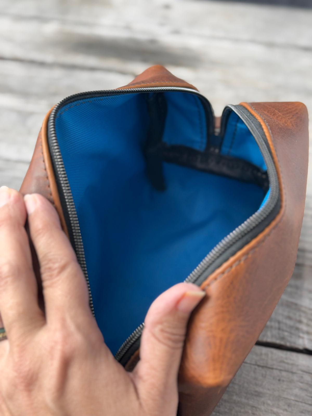 Close-up of brown leather Dopp kit zipper pull and handcrafted leather end tab