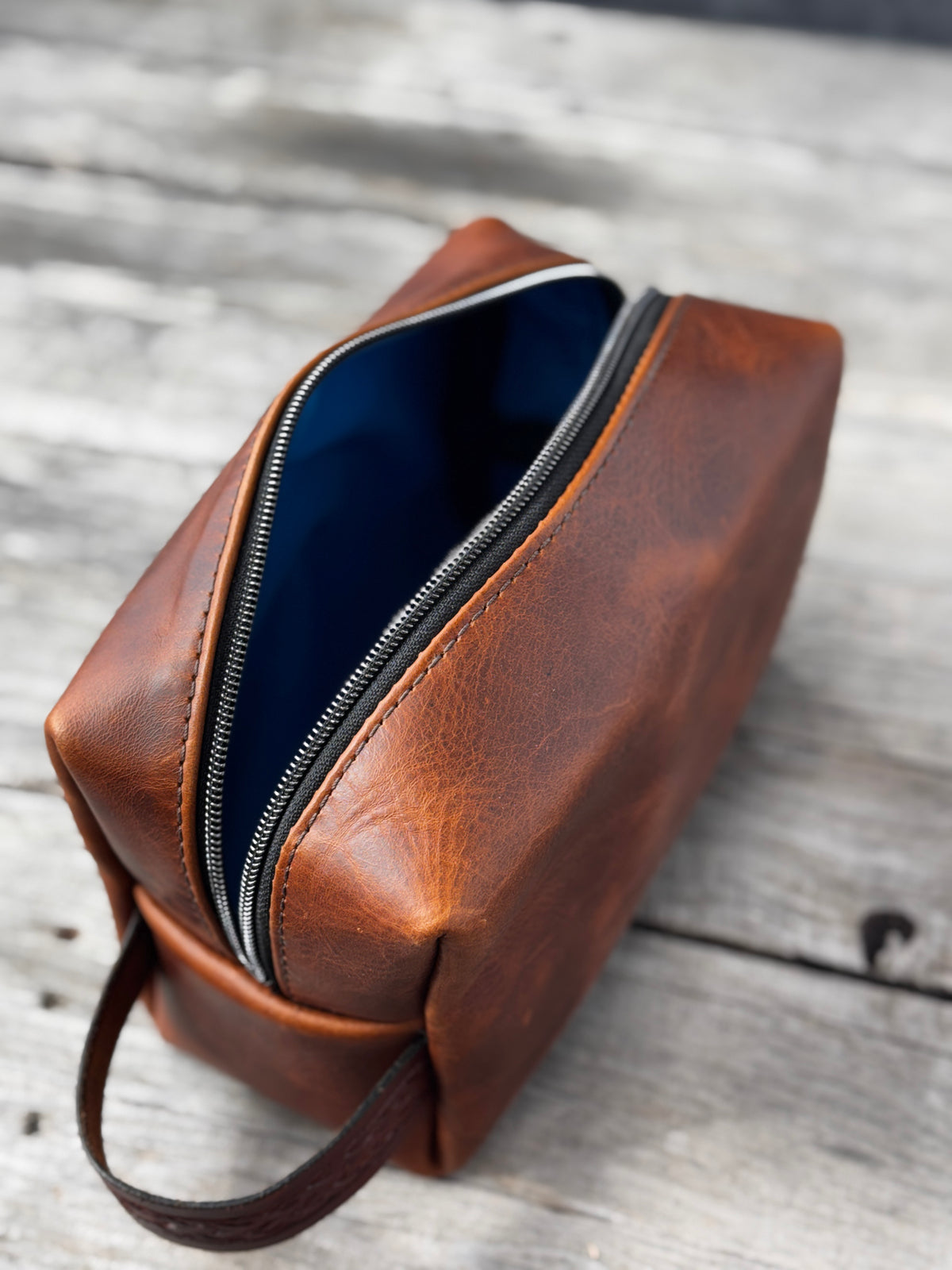 Open brown leather Dopp kit showing bright turquoise waterproof canvas interior