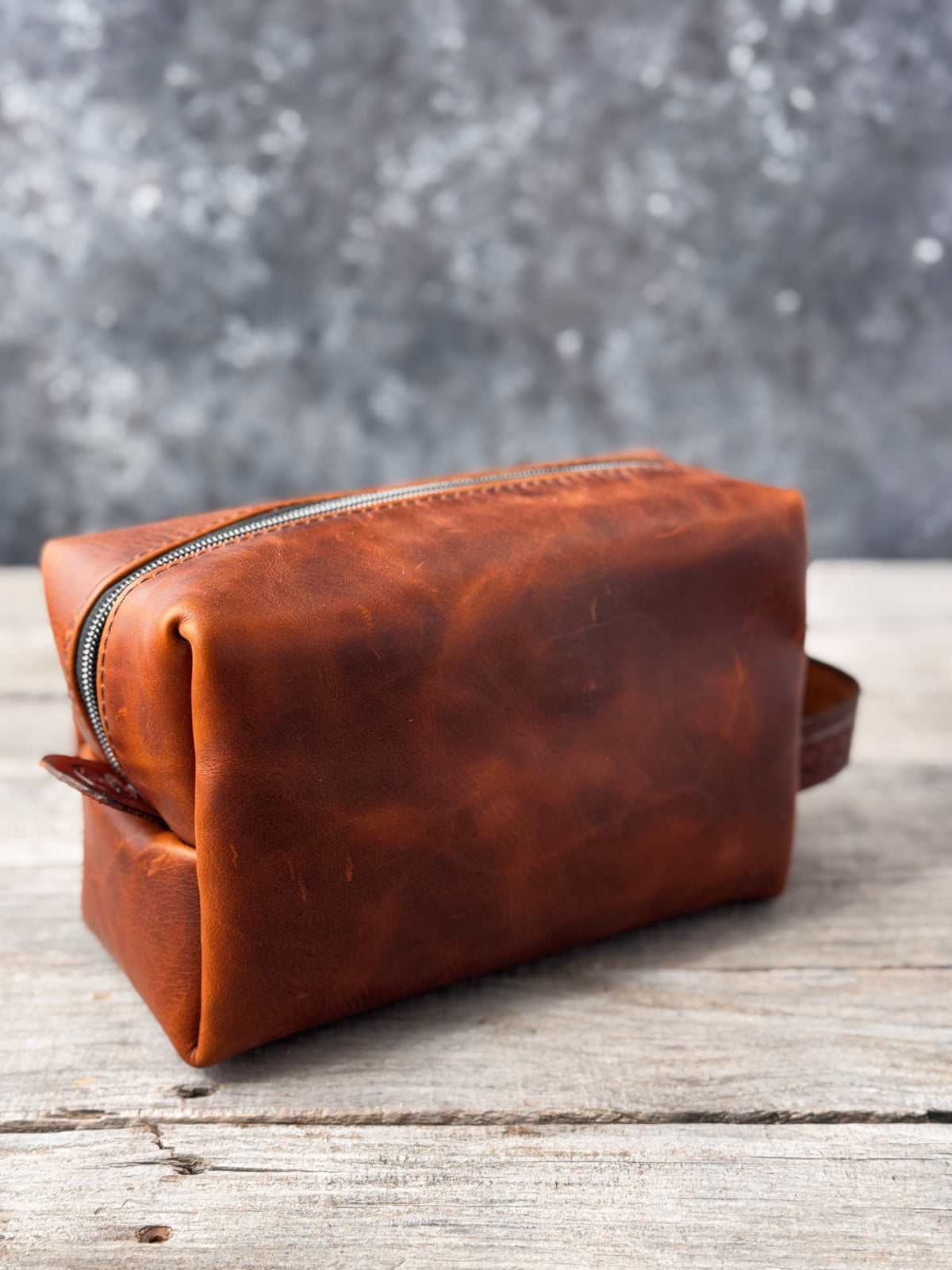 Partially open brown leather travel toiletry bag with turquoise canvas lining