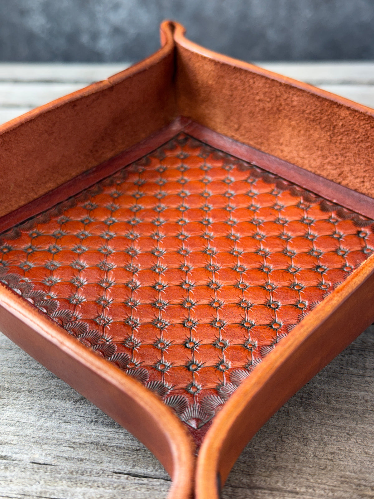 Custom leather valet tray with a hand stamped quilt pattern on a wood background.