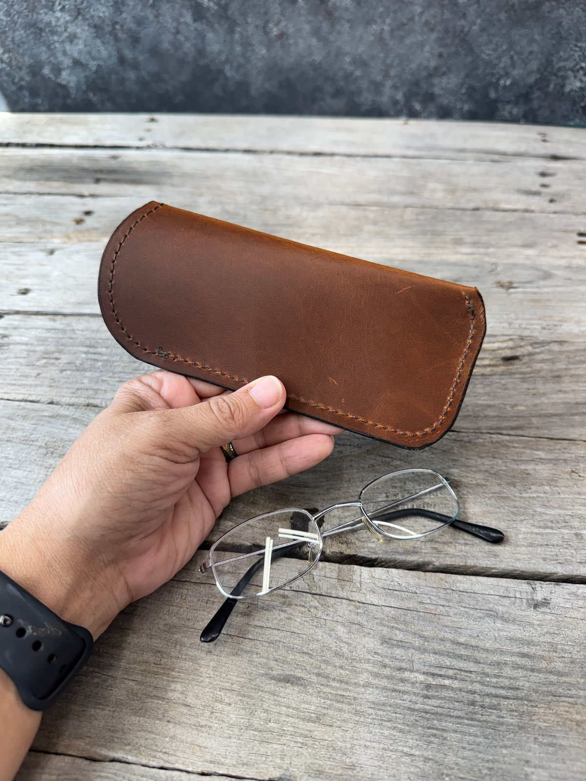 Rustic brown full grain leather eyeglass case held in hand